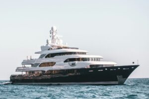 A modern superyacht cruising through the Mediterranean at golden hour, illustrating how vessel size influences overall Mediterranean yacht charter cost.