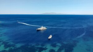 aerial view of superyachts cruising in the mediterranean illustrating operational yacht charter costs
