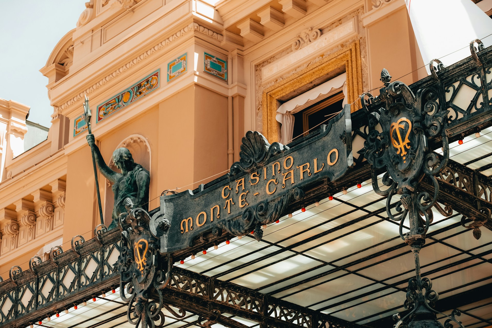 Ornate iron entrance canopy and signage at Casino de Monte-Carlo in Monaco with architectural detailing
