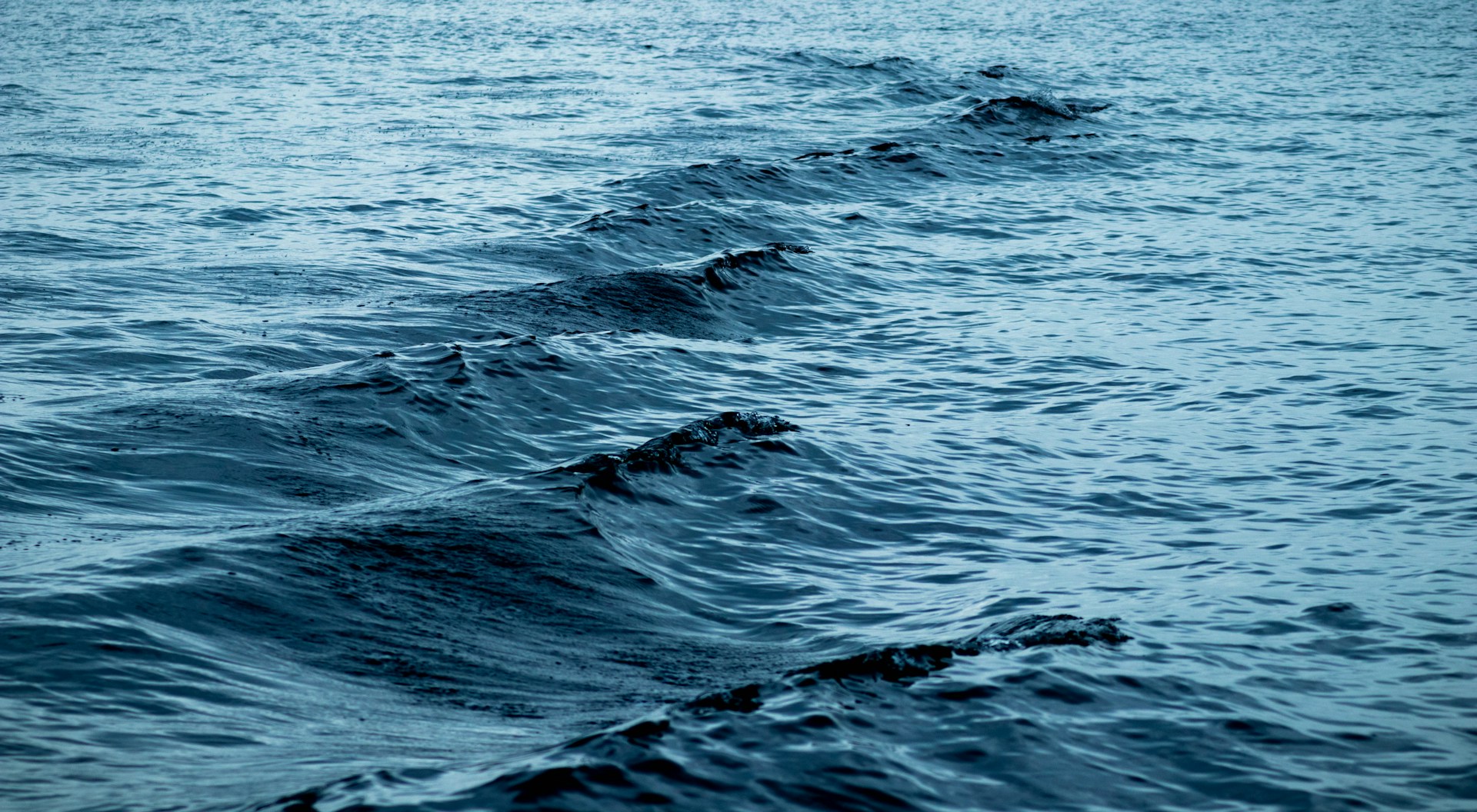 Calm Mediterranean water surface in Monaco harbour with soft light and gentle waves before daily yacht activity